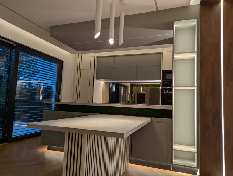 Cuisine sur mesure avec îlot et façades vert-de-gris, colonne vitrine éclairée